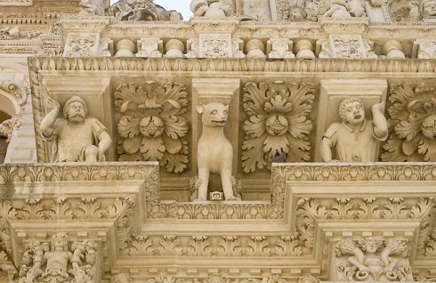 Balkong i barokk stil med intrikat utsmykning av pietra di Lecce, den lokale, lettformede byggesteinen. Legg merke til hendene rundt hundens bein. Balkong i barokk stil med intrikat utsmykning av pietra di Lecce, Lecce, Puglia, Sør-Italia, Italia