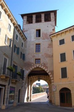 En byport med vakttårn fra middelalderen leder til Ponte Pietra. Foto: Lo Scaligero / Wikipedia Verona, Ponte Pietra, Arena, Piazza delle Erbe, Piazza Signori, Piazza Bra, Unescos liste over Verdensarven, romerriket, antikken, historiske bydeler, gamlebyen, Veneto, Nord-Italia, Italia