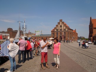 Folk stimler sammen rundt trålerne i Wismars Alter Hafen for å kjøpe fersk eller røkt sjømat. Tollbygningen midt på, byporten Wassertor helt til høyre Wismar, Alter Hafen, Østersjøen, middelalder, Backsteinsgotik, Ostsee, Unesco Verdensarv, Gamlebyen, Altstadt, Hansestadt Wismar, Mecklenburg Vorpommern, Nord-Tyskland