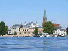 Schwerins Altstadt fotografert fra slottet - teateret til venstre, kunstmuseet til høyre og Dom-kirche i bakgrunnen. Sightseeingturer med båt går fra bryggen til høyre. Her er det også spisesteder med storslått utsikt til Schloss Schwerin. Foto: © Stadtmarketing GmbH Schwerin Schwerin, Altstadt, Theater, Staatsmuseum, Nord-Tyskland