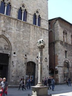 Palazzo Tolomei er det eldste bevarte bolighuset i Siena - bygd før år 1205 - den gang på utsiden av bymuren, som senere ble utvidet. Ulvinnen passer på. Foto: Geobia / Wikipedia Siena, Unescos liste over Verdensarven, historisk, etruskere, middelalder, gamleby, romensk, gotisk, katedral, Toscana, Midt-Italia, Italia