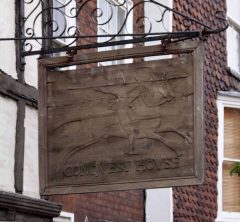 Over inngangsdøren til Conquest House henger dette skiltet. Foto:Tony Hisgett / Wikipedia CC-BY-SA-2.0 Canterbury, Cathedral, West gate, Christ Church Gate, Minster, Thomas Beckett, England, River Stour, The Weavers, romertid, middelalder, early british gothic, Storbritannia